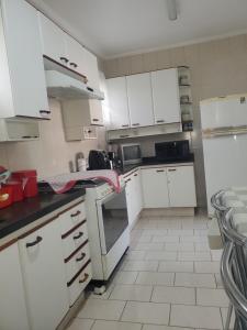 a kitchen with white cabinets and white appliances at Rios Home in Poços de Caldas