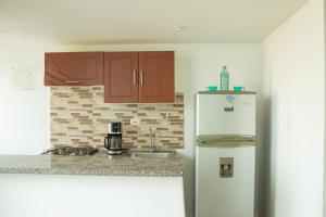 a kitchen with brown cabinets and a white refrigerator at apartamento con alma 888 in Coveñitas