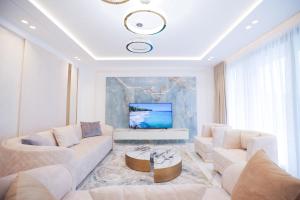 a living room with white furniture and a tv at Palmera Vip Villa in Sarandë