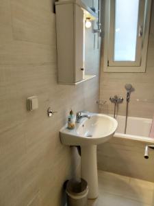 a bathroom with a white sink and a bath tub at Andros Guesthouses in Andros