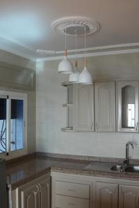 a kitchen with white cabinets and a sink and lights at Apartamentos de Fola 3 in Asilah