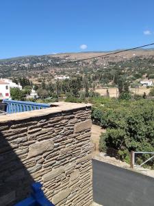 a stone wall with a view of a city at Andros Guesthouses in Andros