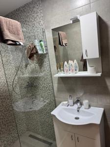 KravljaにあるApartments Indigoのシャワー、洗面台、鏡を備えたバスルーム +3枚の写真
