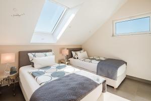 a attic bedroom with two beds and a window at Design-Wohnungen by Ulrike Horster in Bensheim