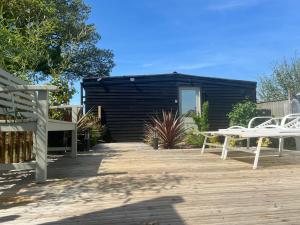 怀门德姆Lavender Lodge - Pool and Hot Tub with sunset views over open fields的有两张白色桌子和黑色建筑的露台