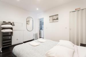 een witte kamer met een bed en een spiegel bij Casa do Pereira in Lissabon