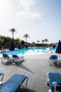 a large swimming pool with chairs and umbrellas at Bungalow - Playa Meloneras in San Bartolomé de Tirajana