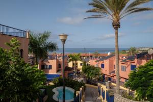 a view of a town with a palm tree and the ocean at Bungalow - Playa Meloneras in San Bartolomé