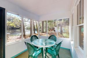 een tafel en stoelen in een kamer met ramen bij Fishermans Cottage in Manitowish Waters