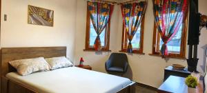 a bedroom with a bed and a chair and windows at Summerbreath Apartments in Ahtopol