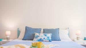 a bed with blue and white pillows and cups on it at 006B - Casa Mare Blu, CENTRO di Riva Trigoso e 300m dalla SPIAGGIA in Riva Trigoso
