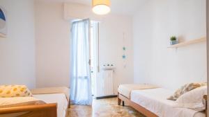 a small room with two beds and a window at 006B - Casa Mare Blu, CENTRO di Riva Trigoso e 300m dalla SPIAGGIA in Riva Trigoso