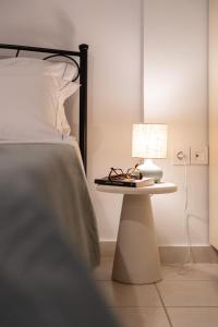 Una cama con una mesa con una lámpara y gafas. en Elaia Boutique Apartment, en Pylos