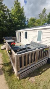 a deck with a couch and chairs on a trailer at MOBILHEIM HERZ LAUWERSOOG - Chalet Schildhoek in Lauwersoog