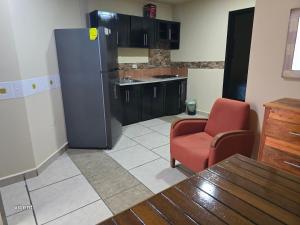 a kitchen with a refrigerator and a red chair at bamboo blvd 1 recamara in Paraíso