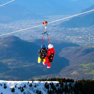 two people are riding on a parachute on a mountain at Charmant appartement au pied des pistes in Chamrousse