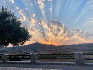 a sunset over a field with a fence and mountains at Maravites Cottage in Zefiría