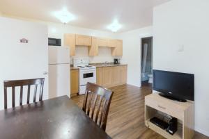 a kitchen with a dining room table and a television at Beachside Motel in Penticton