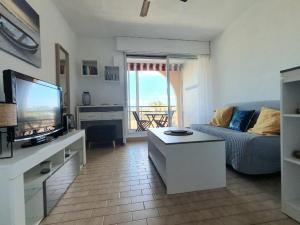 a living room with a couch and a tv at Charmant 2 pièces, Vue sur Mer - Proche Plage in Sète