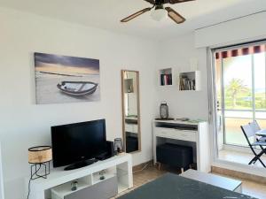 a living room with a flat screen tv and a table at Charmant 2 pièces, Vue sur Mer - Proche Plage in Sète