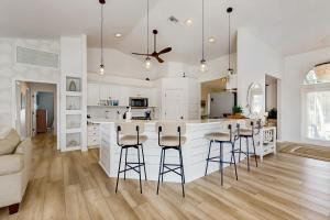 a kitchen with white cabinets and bar stools at The Castaway House in Marco Island
