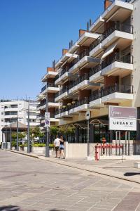 two people walking down a street in front of a building at APPARTAMENTO MARCONI B1 s in Lido di Jesolo