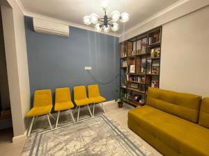 Una sala de estar con sillas amarillas y un sofá. en Milana, en Bishkek
