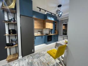 una cocina con armarios azules y una silla amarilla en Milana, en Bishkek