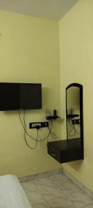 a bedroom with a flat screen tv on the wall at Suganya Lodge in Virudunagar