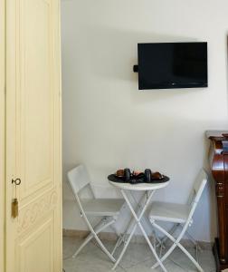 a table with two chairs and a tv on a wall at Blue Marine Affitta Camere in Porto Cesareo