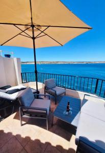 a patio with chairs and a table and an umbrella at Seafront apartment Terrace, lounger & Panoramic ocean views in Mellieħa
