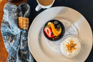 a plate with a bowl of fruit and a cup of coffee at The Cooper's Inn in Shelburne