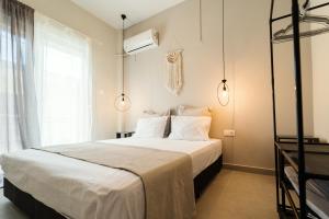 a bedroom with a bed with white sheets and a window at Styliani's Cozy Apartment in Iraklitsa