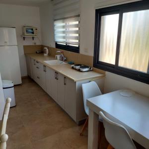 a kitchen with a sink and a table and a refrigerator at יחידת אירוח גלילי in Qiryat Shemona