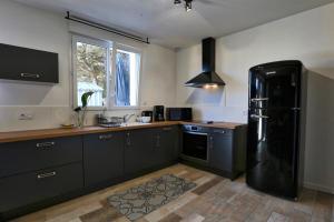 a kitchen with a black refrigerator and a window at Villa Thaïlande - Domaine Le Sherwood in Notre-Dame-de-Monts