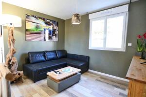 a living room with a black leather couch and a table at Villa Thaïlande - Domaine Le Sherwood in Notre-Dame-de-Monts