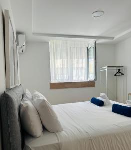 a bedroom with a white bed with pillows and a window at Suitenes Coast in Rethymno Town +74 photos