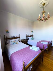 a bedroom with two beds and a chandelier at Arrochela apartamento in Ribeira