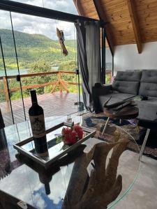 een woonkamer met een glazen tafel en een fles wijn bij Bangallo Dona Maria in Nonoai