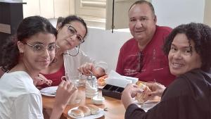a group of people sitting around a table eating food at Rio Vibes Hostel - Hostel na Glória, AC, Social Vibe & Próximo a Lapa in Rio de Janeiro