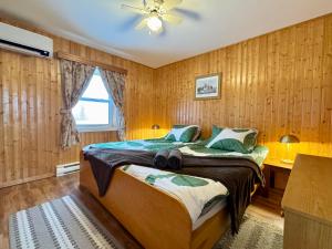 a bedroom with a bed with wooden walls and a ceiling at The Great Cabot Lodge in Baddeck