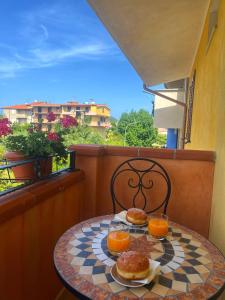 a table with two donuts and oranges on a balcony at Appartamento il Lentischio a 5 minuti dal mare a Cardedu in Cardedu
