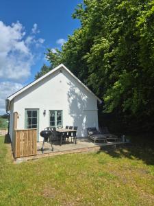 a white shed with a picnic table and a grill at Mysigt hus i liten by nära havet in Ystad