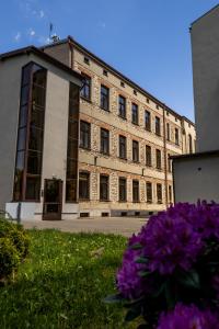 Un edificio antiguo con flores moradas en el frente. en Nowe - PERŁA ŚRÓDMIEŚCIA & Free Parking 48m2, en Częstochowa