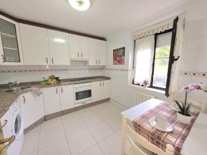 a kitchen with white cabinets and a table and a sink at La Casa de Lidya - 36801 in Entrambasaguas