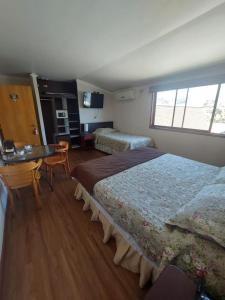 a bedroom with two beds and a desk and a window at Hotel Cerro Castillo in Viña del Mar