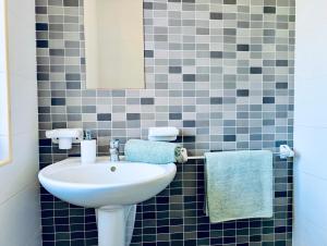 a bathroom with a white sink and blue tiles at Sunset Haven Manikata - Walking distance to Golden Bay in Manikata