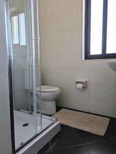 a bathroom with a toilet and a glass shower at Sunset Haven Manikata - Walking distance to Golden Bay in Manikata