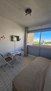 a bedroom with a bed and a table and a tv at Studio - 2min Mer & Plages - Grau du Roi in Le Grau-du-Roi