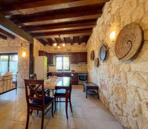una cucina con tavolo, sedie e parete in pietra di Villa Posidi with Private Pool and Sea View a Possidi